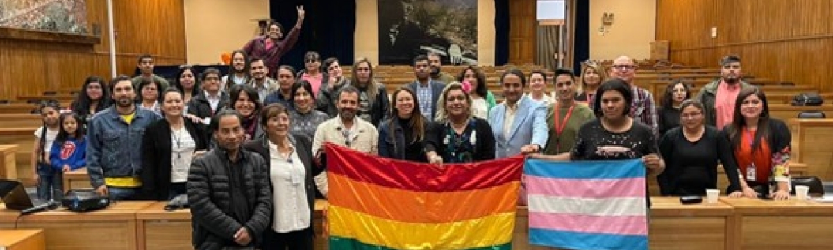 Personas en un salón sosteniendo bandera LGTBIQ+