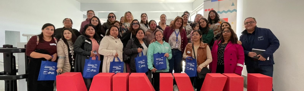 Grupo de personas de pie detrás de letras grandes que conforman la sigla MINVU