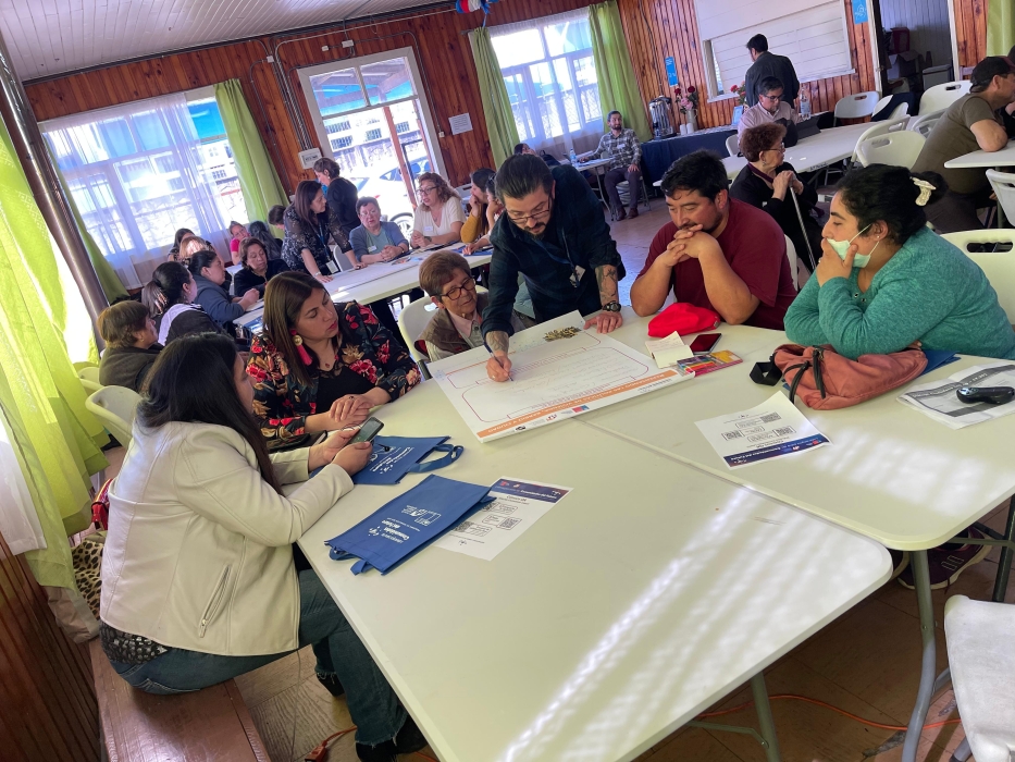 Grupos de personas en mesas trabajando en papelógrafos 
