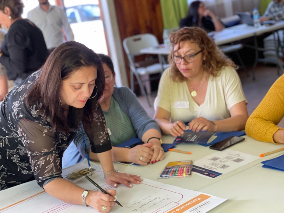 Mujeres sentadas en mesa trabajando en papelógrafo 