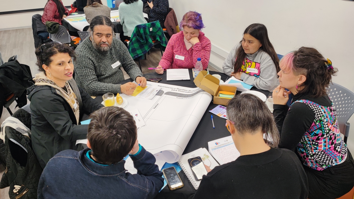 Un grupo de personas conversan sentados en una mesa redonda
