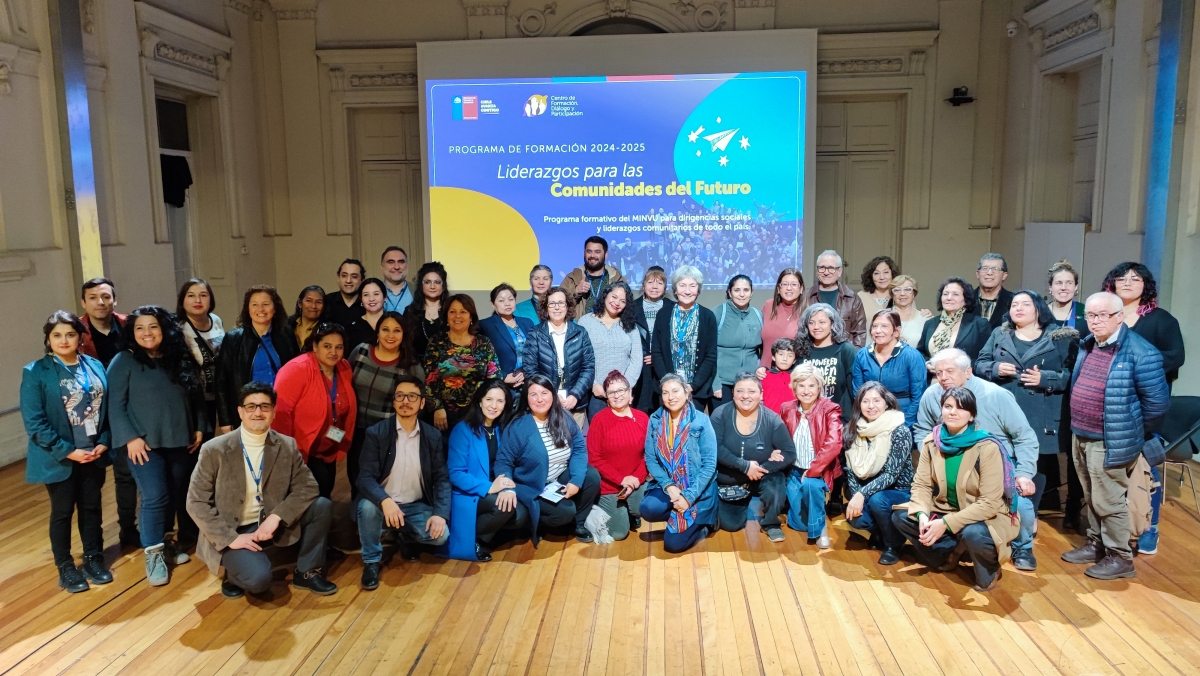 Grupo numeroso de personas posa para fotografía en un salón