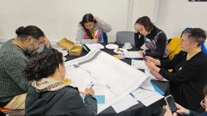 Un grupo de personas sentados en una mesa redonda escribe en papeles