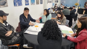 Un grupo de personas conversan sentados en una mesa redonda