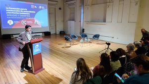 Funcionario habla desde podio a personas sentadas en salón