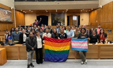 Personas en un salón sosteniendo bandera LGTBIQ+