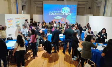 Muchas personas reunidas alrededor de mesas realizando un ejercicio colaborativo de coordinación