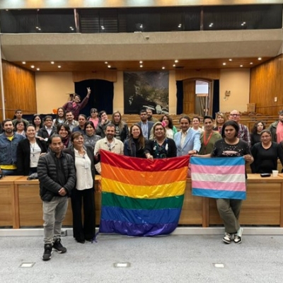 Personas en un salón sosteniendo bandera LGTBIQ+