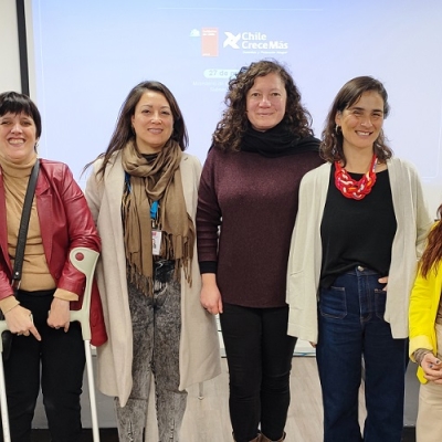 Seis mujeres sonriendo para la fotografía frente a una pantalla