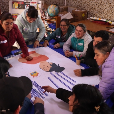 Grupo de personas de pie y sentadas alrededor de una mesa trabajando en un papelógrafo